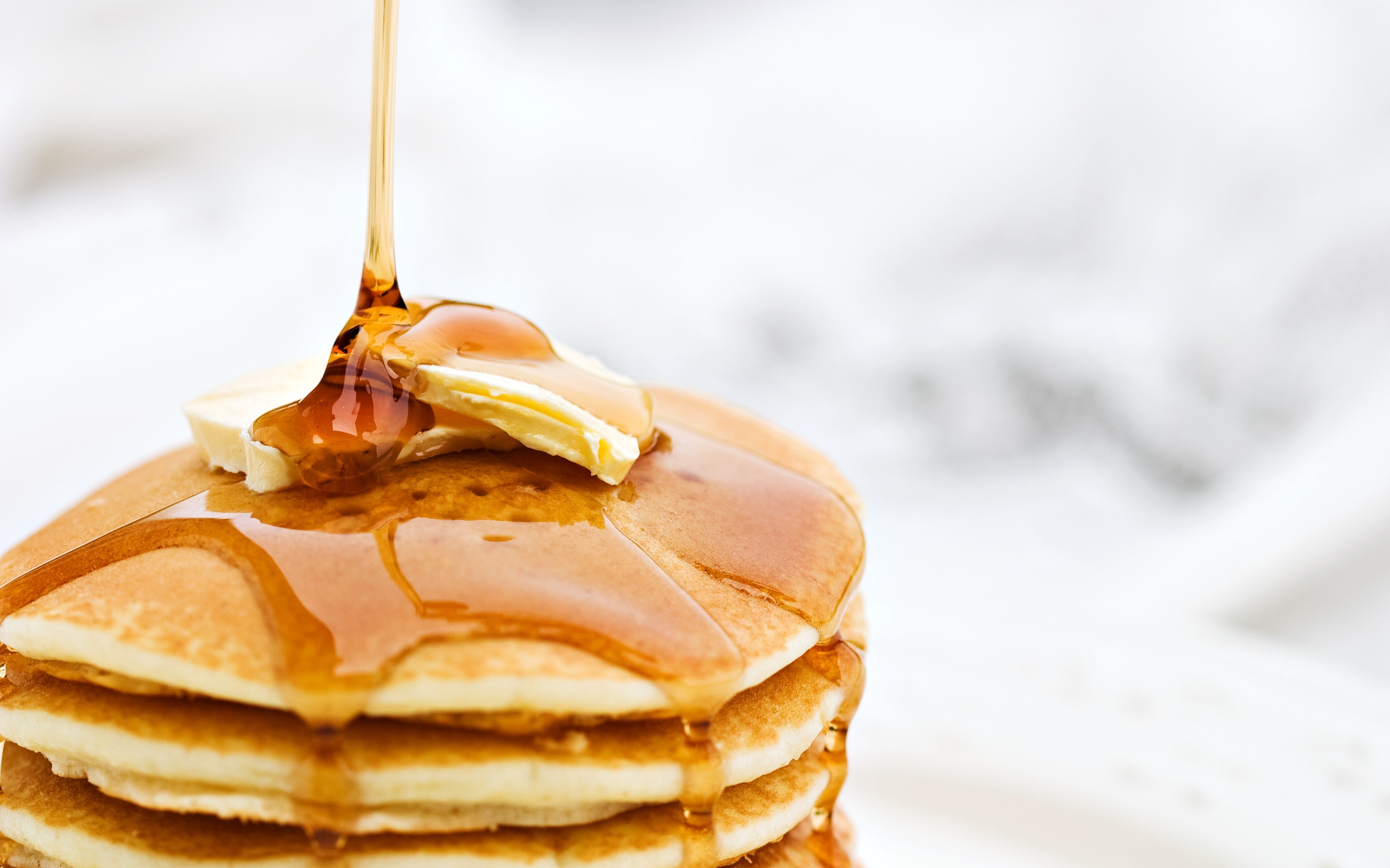 Honey being drizzled onto buttered pancakes
